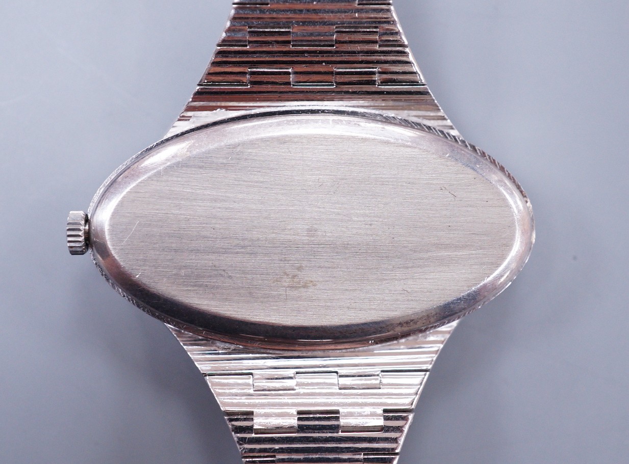 A lady's 1970's silver Longines manual wind wrist watch, with oval dial, on a textured silver bracelet.